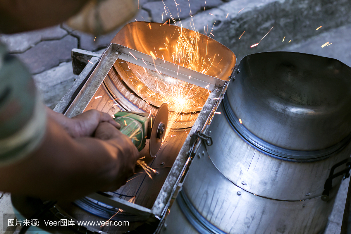 工人们使用金属磨床切割钢制品,产生火花。